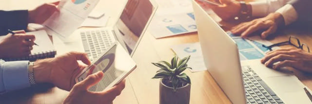 Geschäftstreffen mit mehreren Personen, die an Laptops und Tablets arbeiten, symbolisiert die Einhaltung des Verhaltenskodex Röckelein.